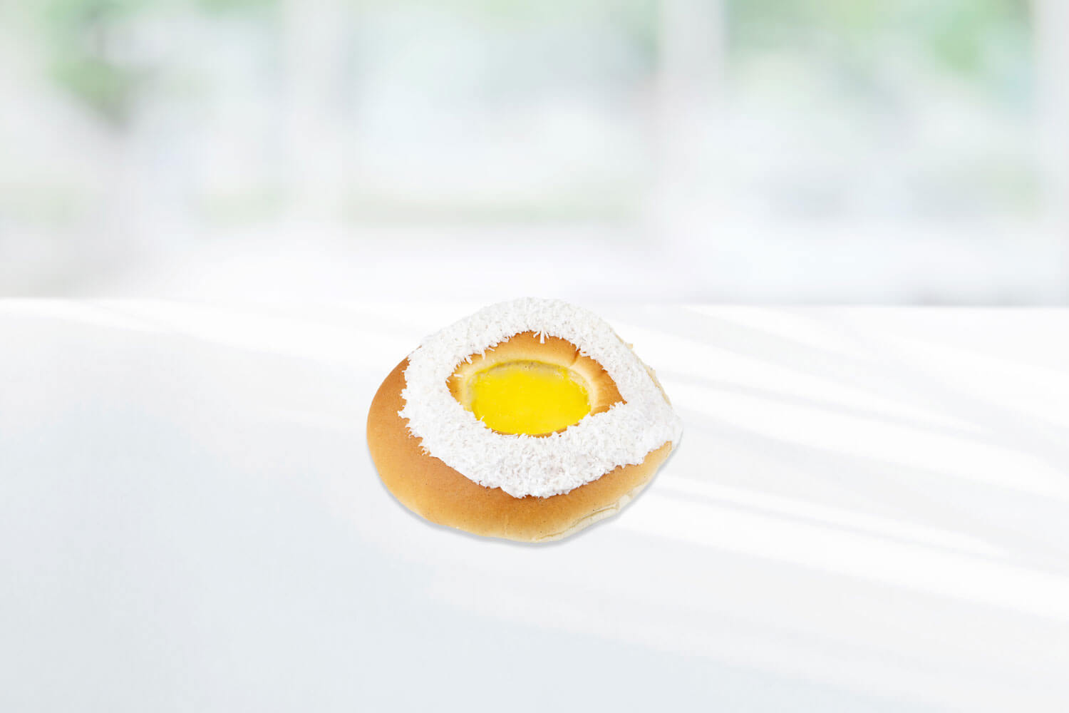 Skolebrød pyntet med hvit melisglasur med kokosmasse og gul vaniljeplomme