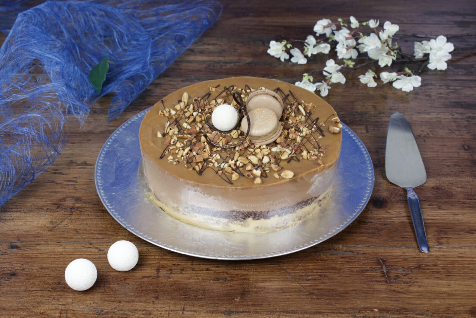 Karamellfristelsekake med melkesjokolademousse og karamellganache, pyntet med makroner og nøtter